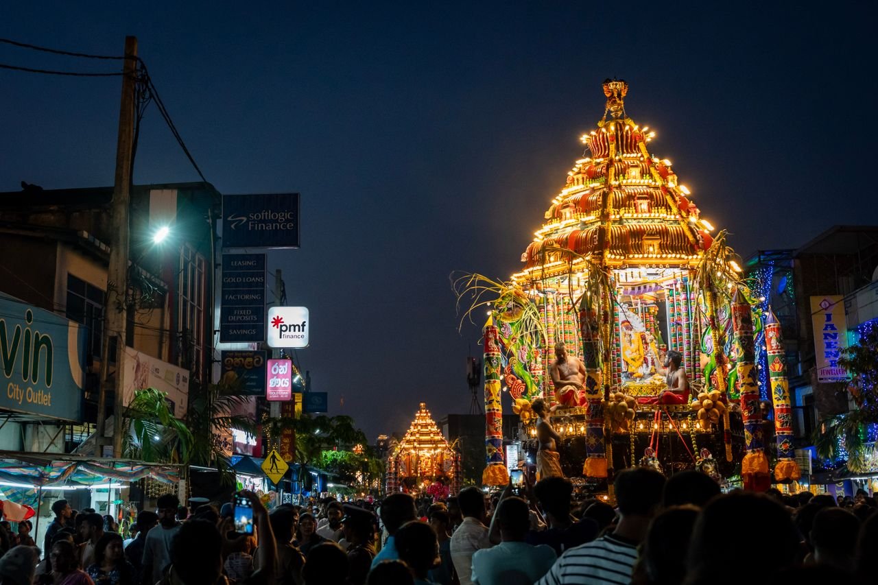 Glimpse of a colorful procession during a Hindu festival at night with crowds gathering in celebration.